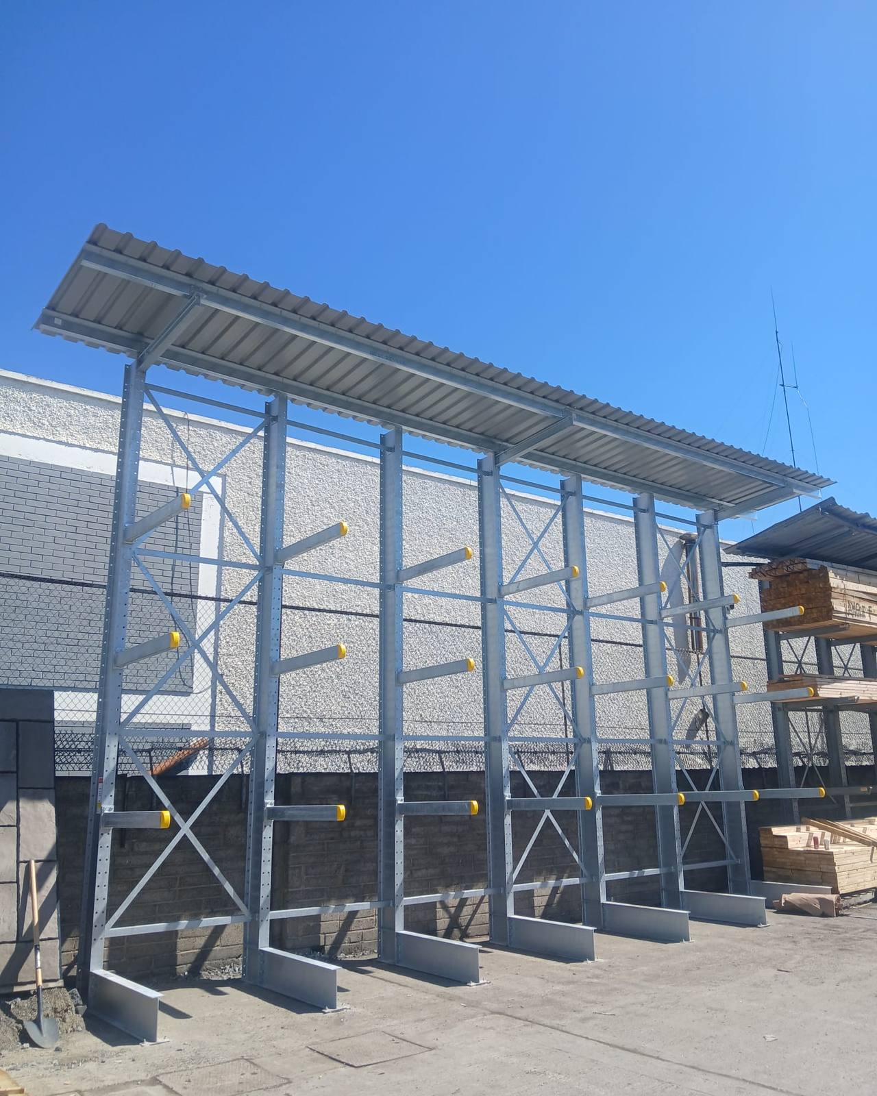 Galvanised external cantilever racking with a steel roof, built against a boundary wall