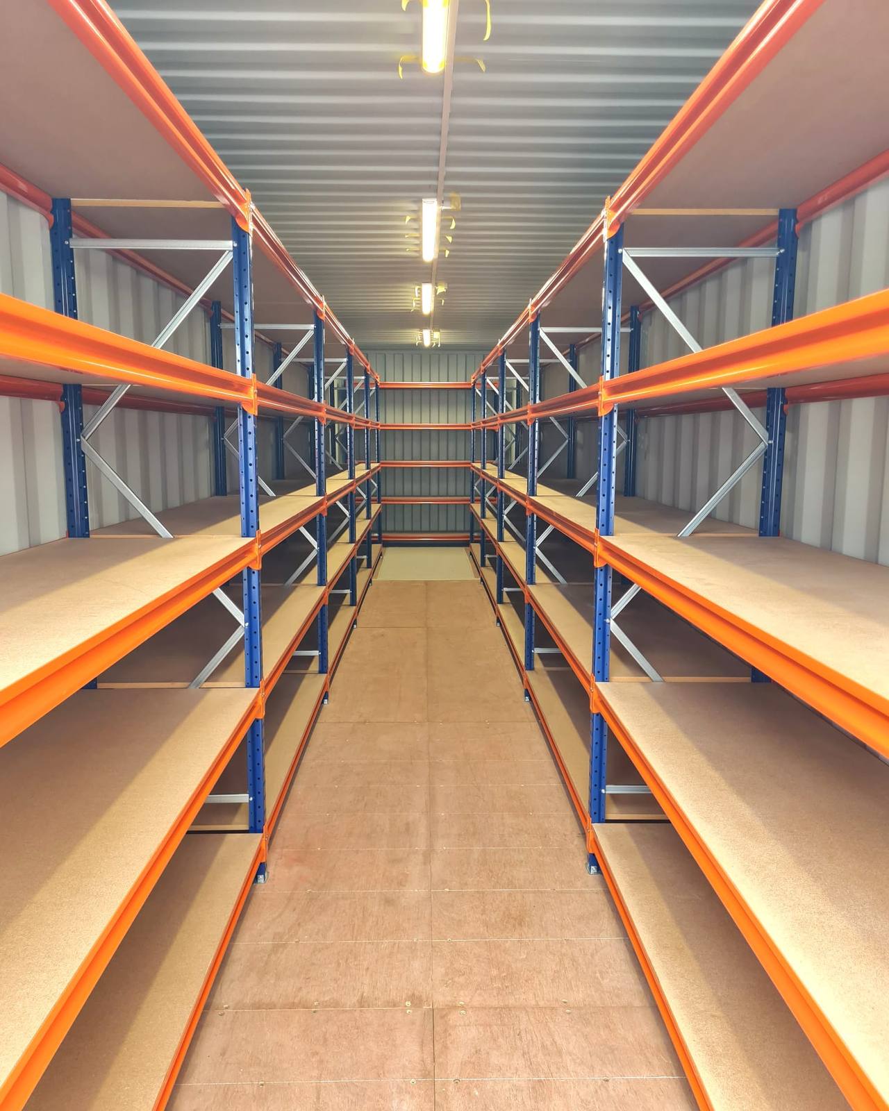 Inside a shipping container with shelving down both walls and a clear walkway between them