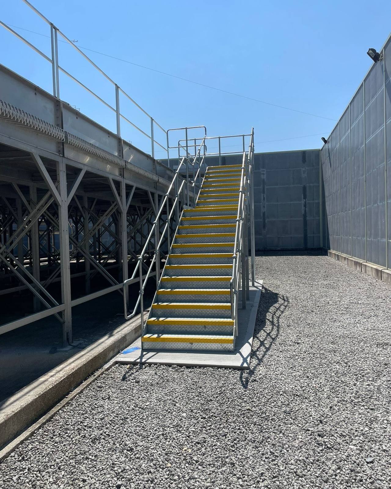Galvanised external staircase with yellow step nosings leading up to a steel platform