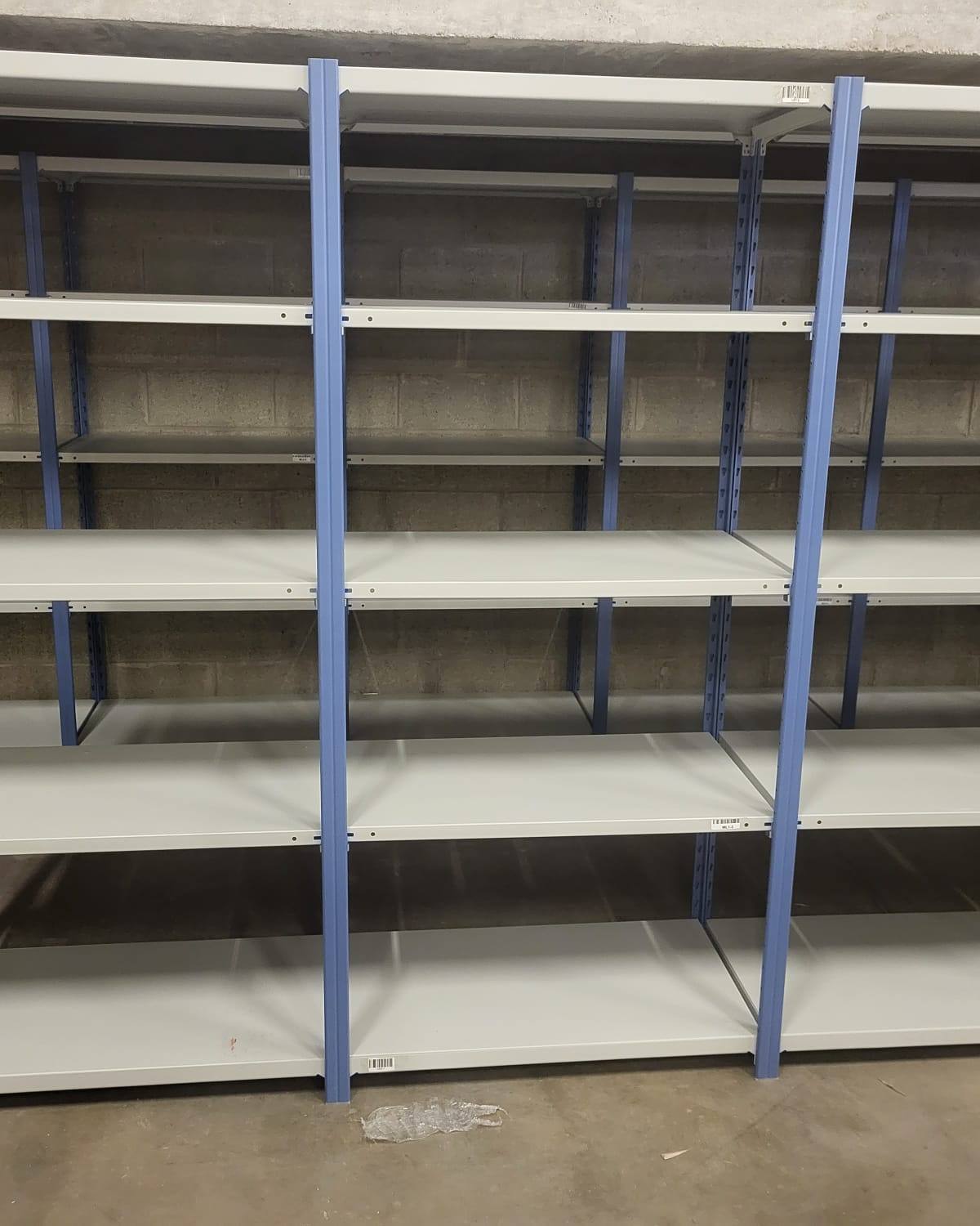 End of a run of grey modular shelving bays with blue uprights in a warehouse