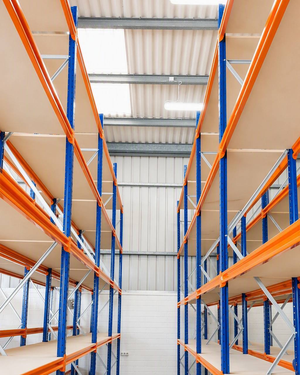 Pallet racking run seen down the aisle, orange beams on blue uprights