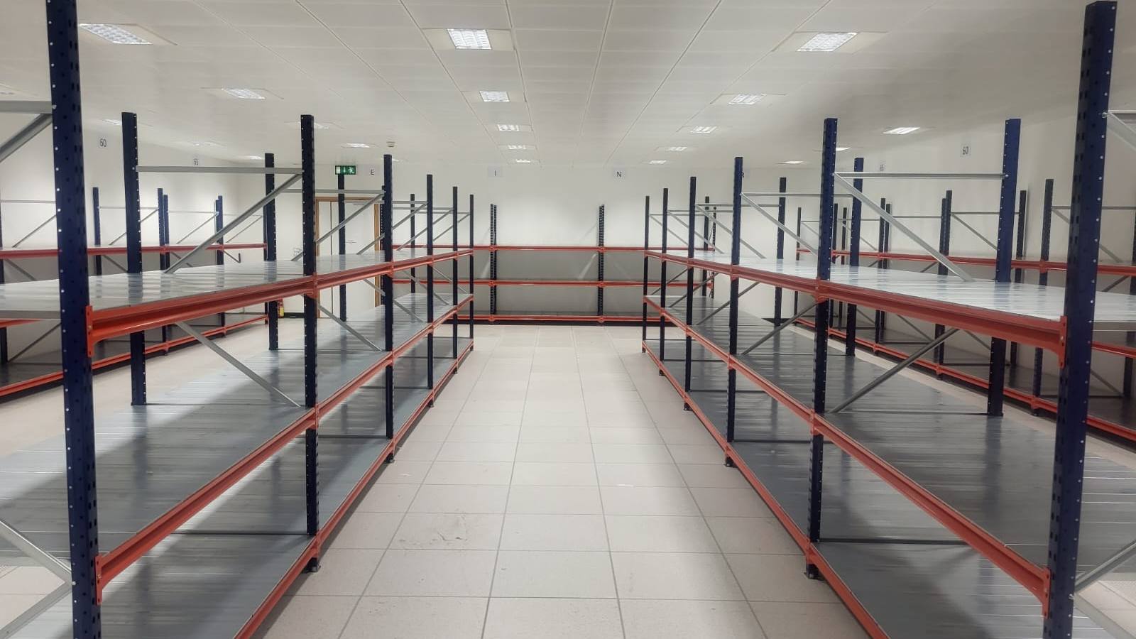 Shelving fitted along both walls of a tiled stockroom